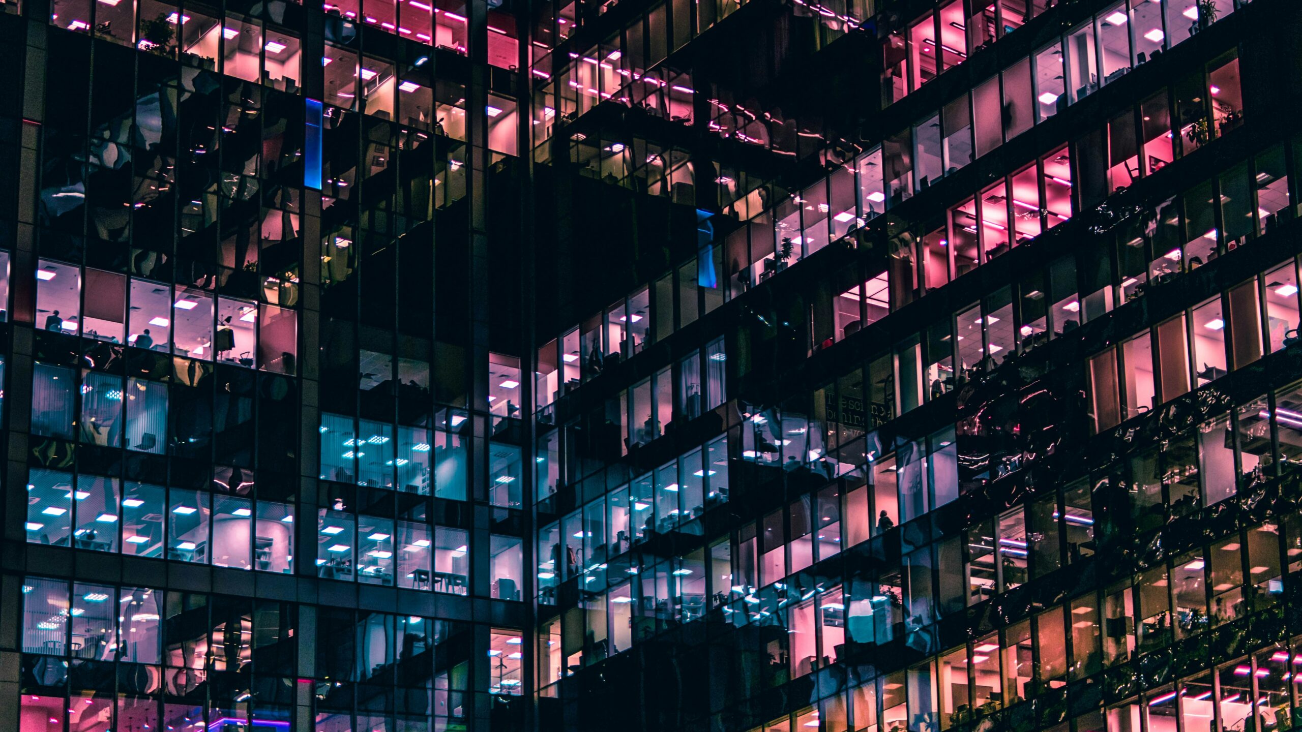Lighted building windows in pink and blue at night