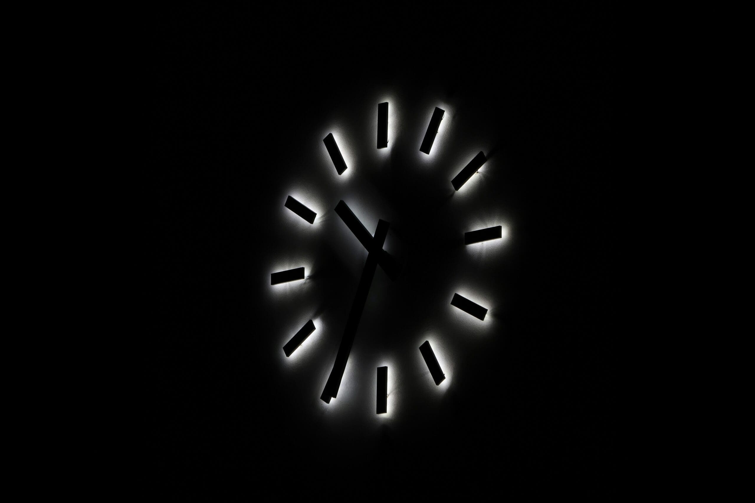 A decorative image of a clock on a black background with ticks instead of numbers and a white backlight.